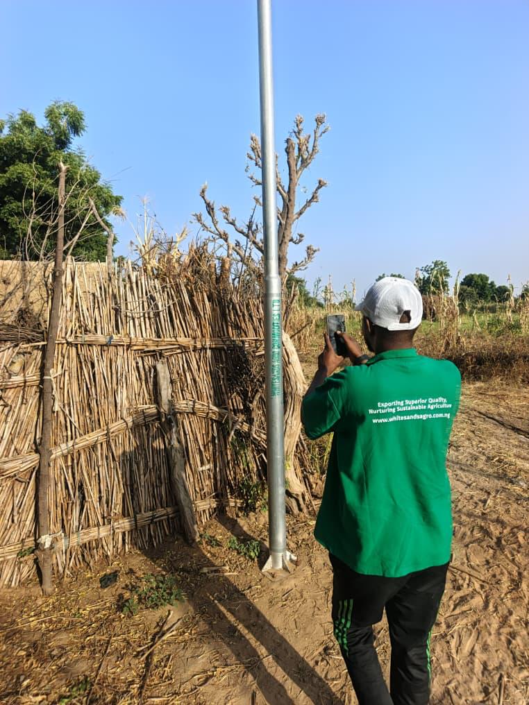 Whitesands Agro field officer documenting a solar-powered streetlight installed for an outgrower community in Northern Nigeria